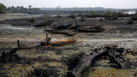 Getty Images Abandoned fishing boats sit aground as crude oil pollution covers the shoreline of an estuary in the Niger Delta region of Nigeria